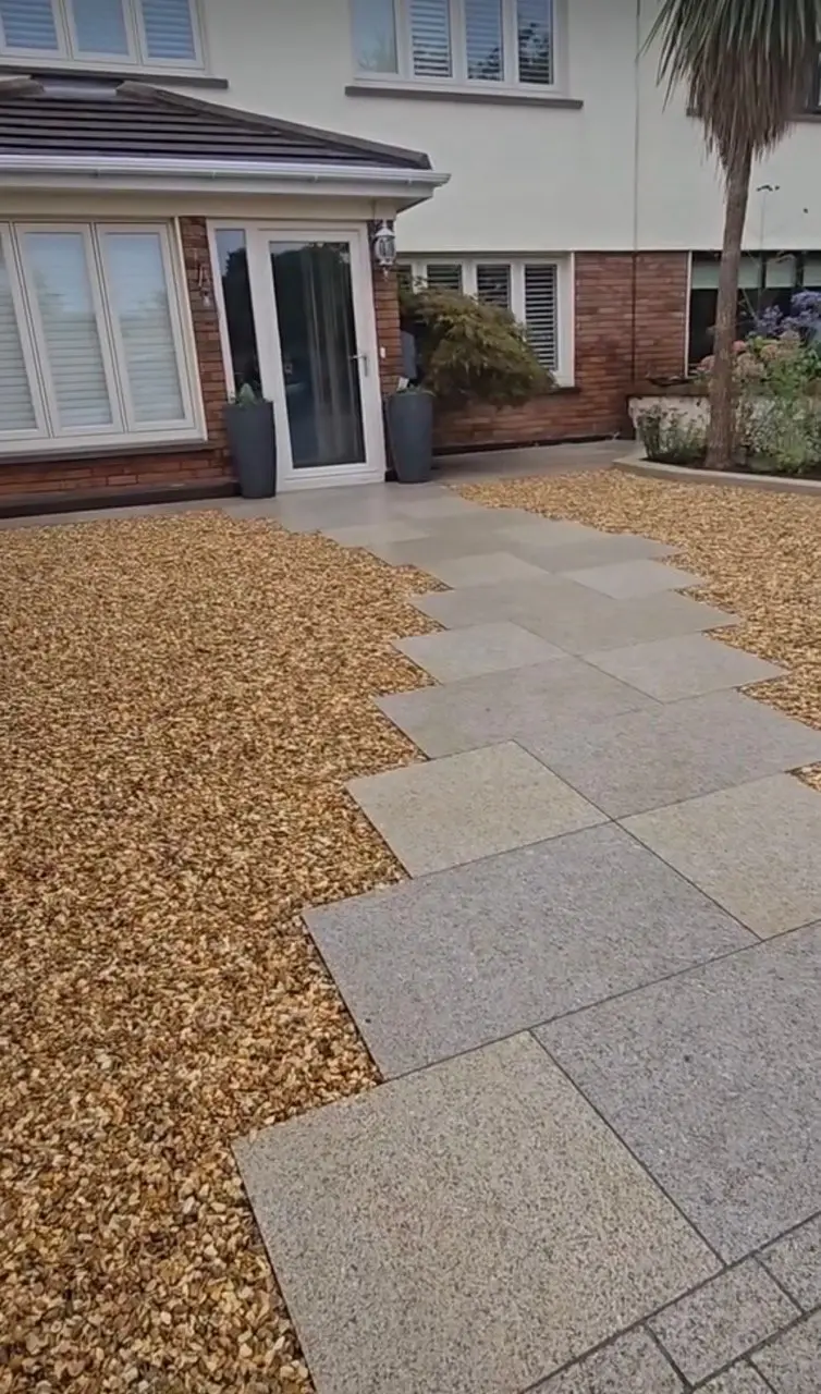 Large-format paver walkway through a gravel front garden to a house entrance